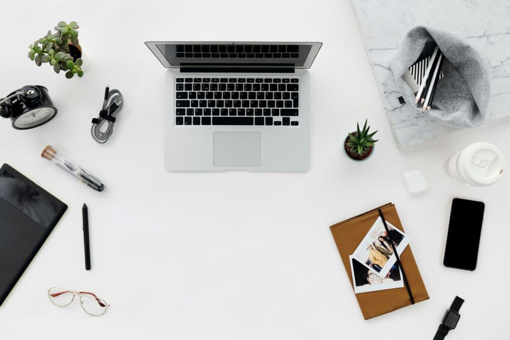 Minimal desk setup with laptop, notebook, phone, and everyday productivity tools to stay consistent when motivation fades
