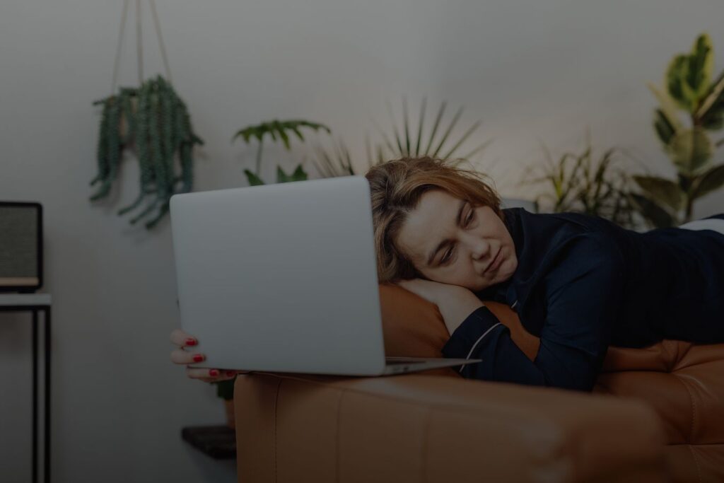 Exhausted person resting beside a laptop showing how ruthless consistency builds freedom through resilience, imperfect progress, and perseverance during difficult seasons
