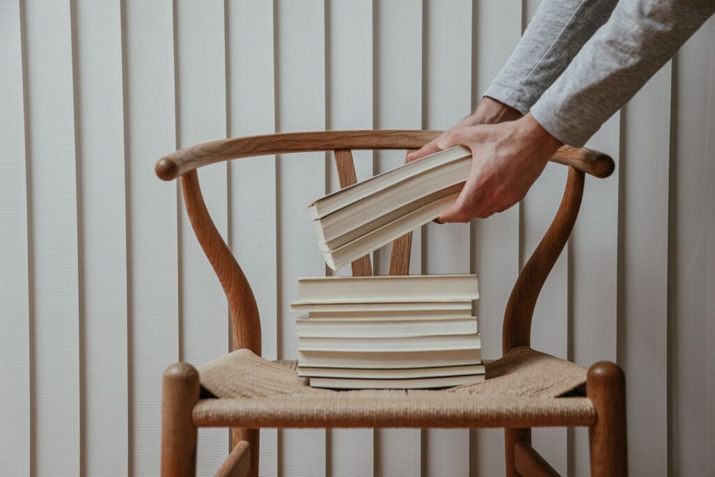 A stack of best books for entrepreneurs being placed on a wooden chair