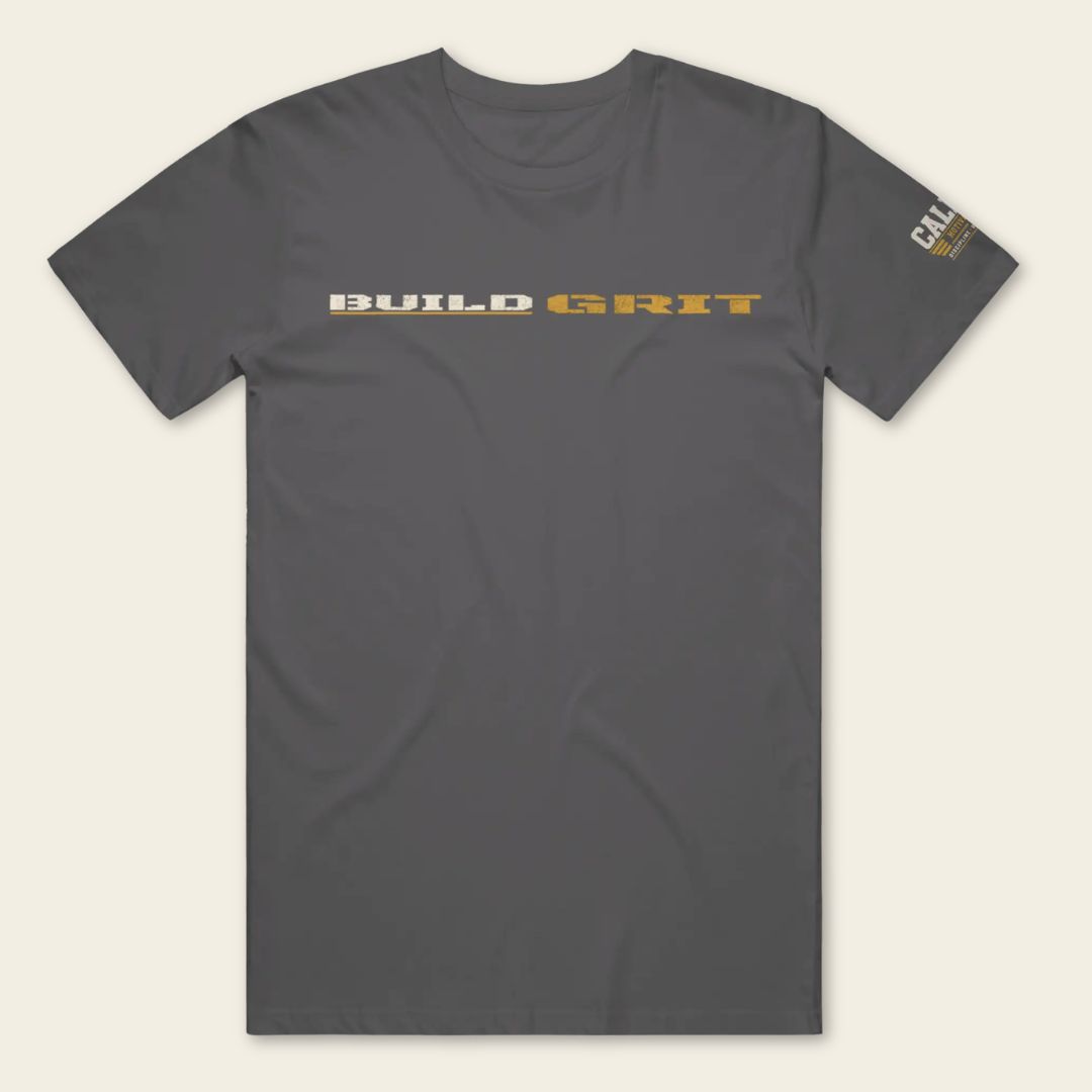 Front view of the BUILD GRIT Premium T-Shirt in Heavy Metal featuring distressed BUILD GRIT artwork and a Caliber Motivation Co. sleeve patch.