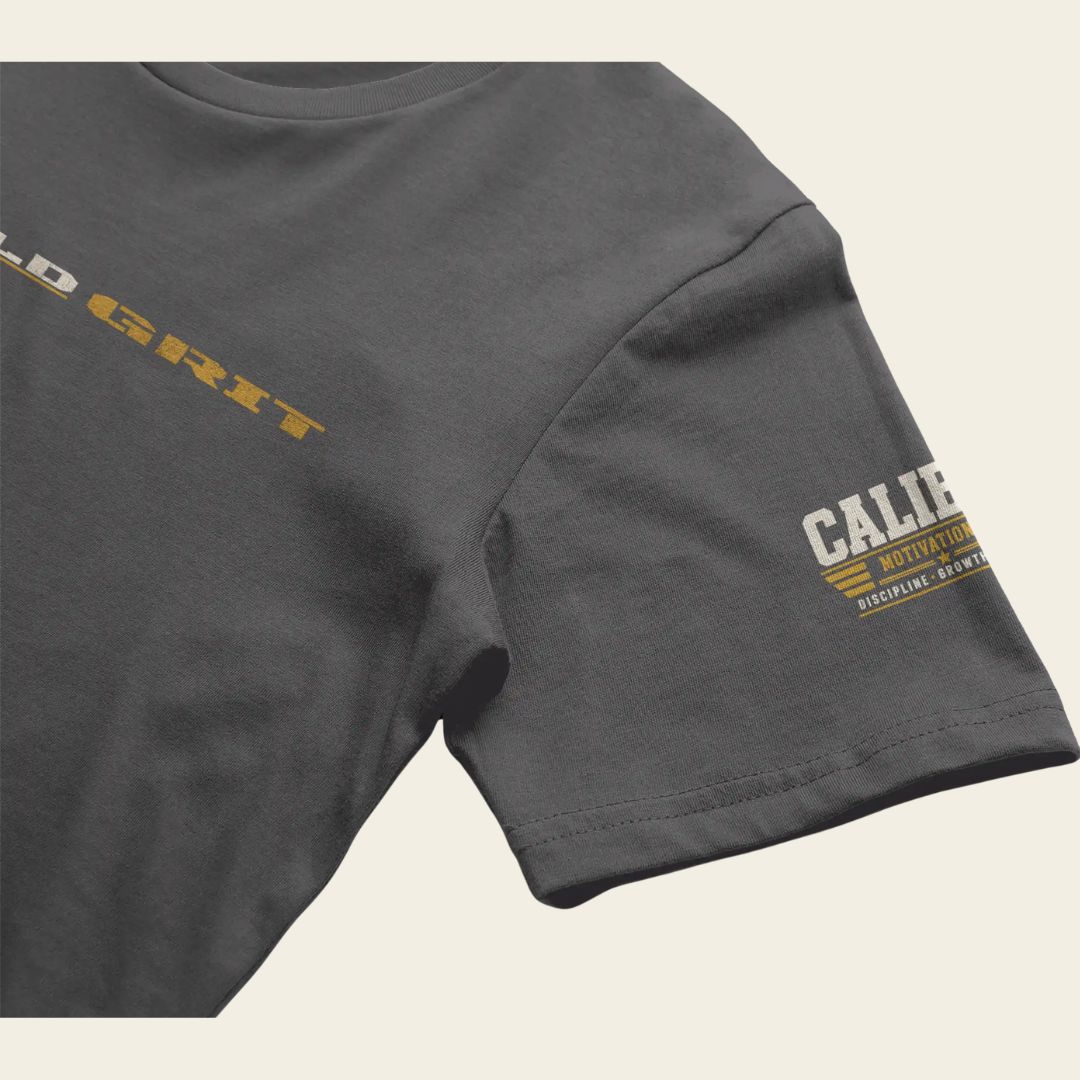 Close-up of the Caliber Motivation Co. sleeve patch on the BUILD GRIT Premium T-Shirt in Heavy Metal.