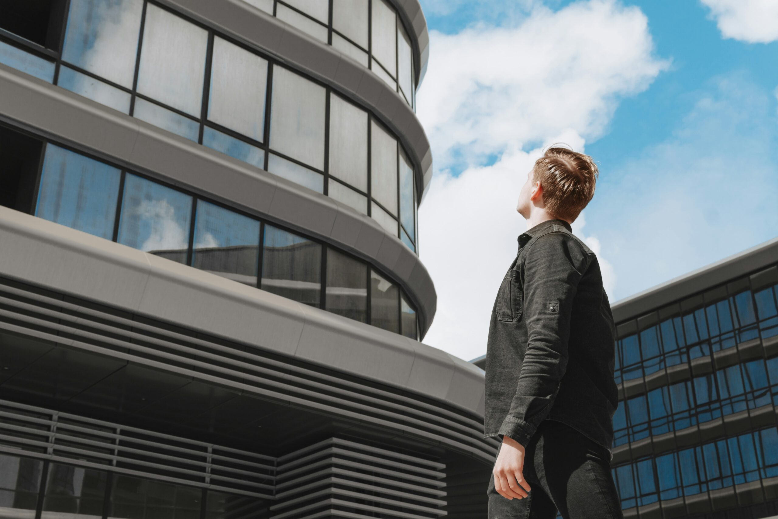 Person looking up at a modern office building representing how to overcome imposter syndrome without waiting for confidence.