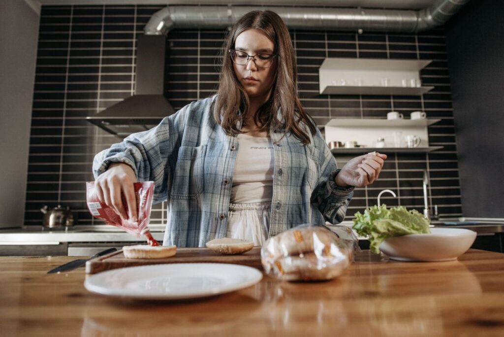 Teen preparing a simple meal in a home kitchen to build life skills.
