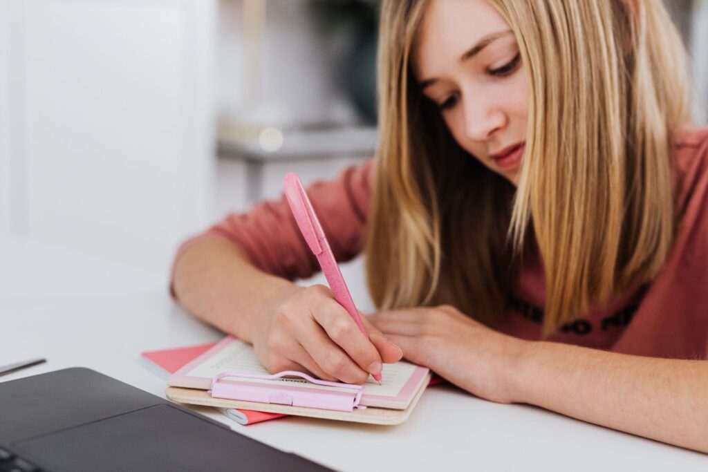 Teen writing in a planner while preparing for adulthood and building essential life skills before turning 18.