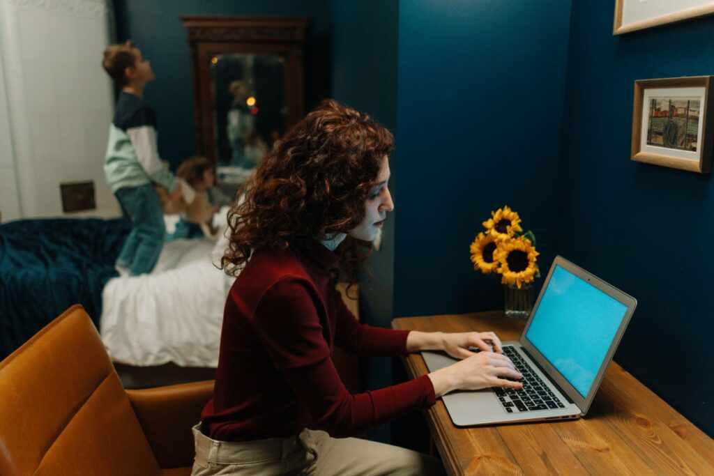 Woman working while family life continues behind her, showing the price of success and sacrifice