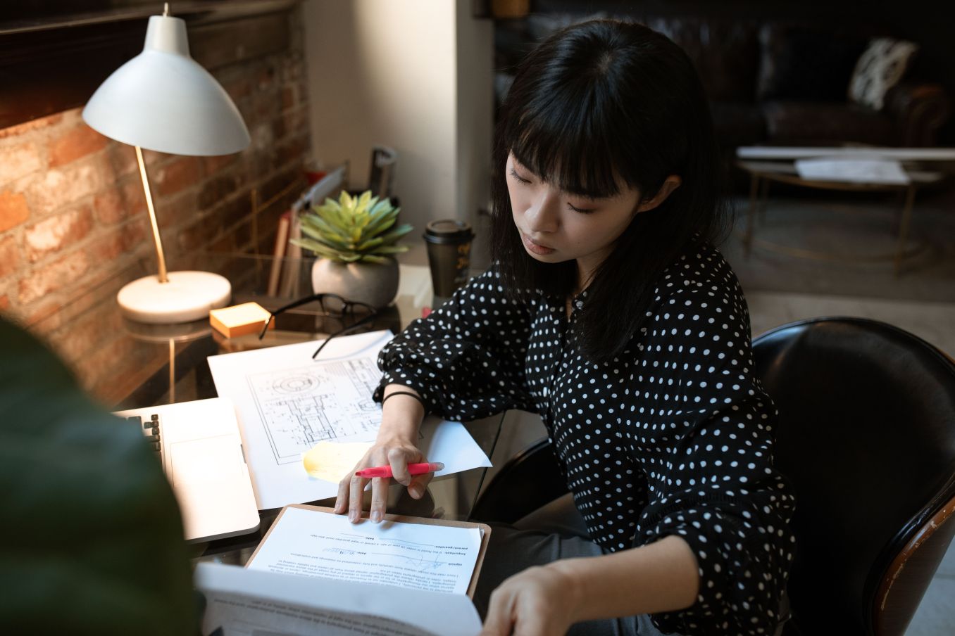 Woman focused on paperwork at her desk, illustrating how to be so productive it feels illegal through deep work and concentration.
