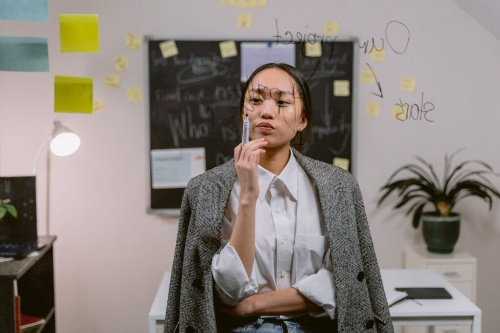 Professional woman studying a planning board while developing a strategy to leave her 9-to-5 job and start a virtual assistant business.
